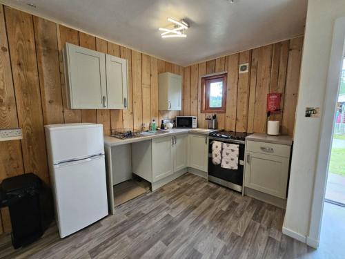 a kitchen with white appliances and wooden walls at Tonita, River Black Water Holiday Lets, INCHBAE, GARVE, IV232PG in Garve