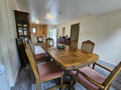 a dining room with a wooden table and chairs at Tonita, River Black Water Holiday Lets, INCHBAE, GARVE, IV232PG in Garve