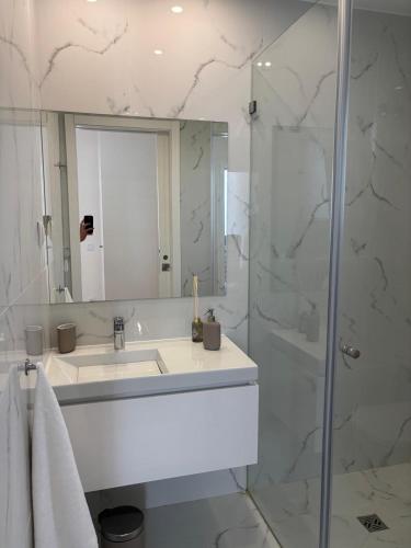 a white bathroom with a sink and a shower at Aroeira Beach Home in Almada