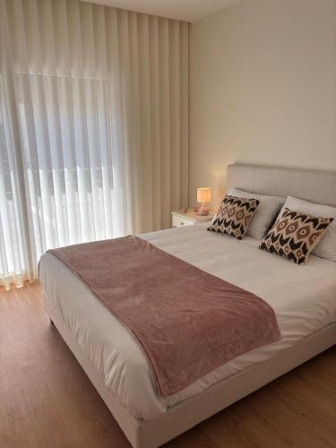 a bedroom with a large white bed with pillows at Aroeira Beach Home in Almada