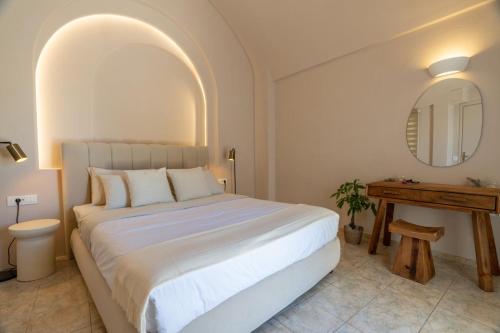 a bedroom with a large white bed and a table at Island Charm Imerovigli Apartment in Imerovigli