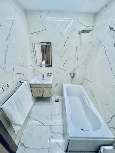 a white bathroom with a tub and a sink at Atta pyramid view inn in Cairo