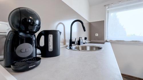 a coffee maker on a counter next to a sink at Kassel - Gemütliches DG Apartment in Fuldatal mit Parkplatz & Wlan - OneN8 in Fuldatal