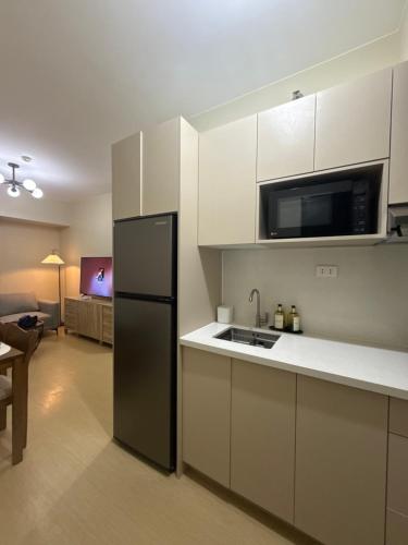 a kitchen with white cabinets and a black refrigerator at Amayara Nest Hospitality 2BR Condo with Netflix in Cagayan de Oro