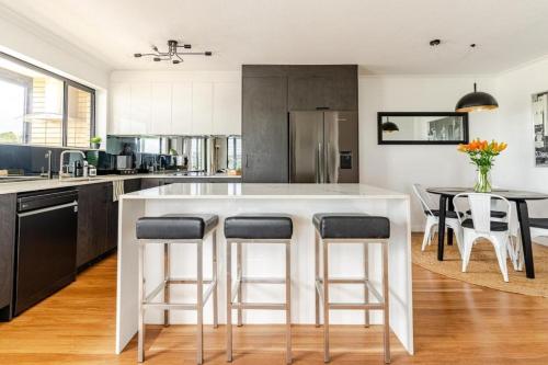 a kitchen with a large white island with bar stools at City View Serviced Apartments in Brisbane