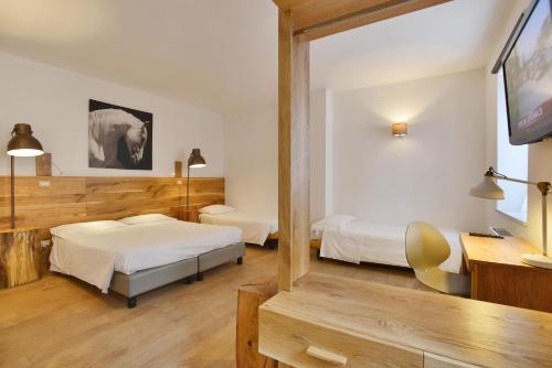 a hotel room with two beds and a flat screen tv at Albergo Les Dependances in Norcia