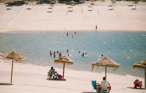 people on a beach with umbrellas and people in the water at Alojamientos rurales La Barca del tío Vito in Peloche