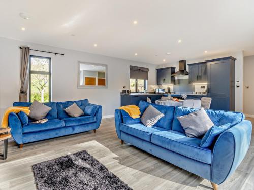 a living room with blue couches and a kitchen at 2 Bed in Heyope 94203 in Knighton