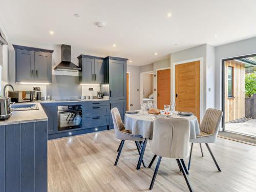 a kitchen with blue cabinets and a table with chairs at 2 Bed in Heyope 94203 in Knighton