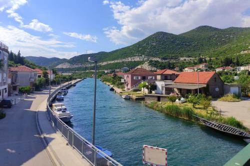 a river with boats in a town with mountains at Holiday house with a parking space Rogotin, Neretva Delta - Usce Neretve - 24802 in Rogotin
