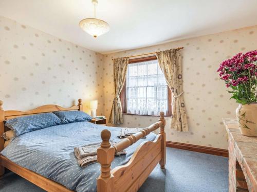 a bedroom with a wooden bed and a window at 3 Bed in Northrepps 88327 in Northrepps