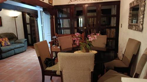 a dining room with a table with a vase of flowers on it at Casa Feliz Antigua in Antigua Guatemala