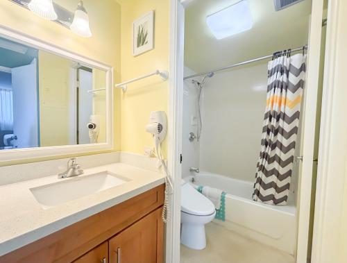 a bathroom with a sink and a toilet and a mirror at Royal Kuhio 1812 - 1BR with partial ocean view in the Heart of Waikiki with Free Parking! in Honolulu