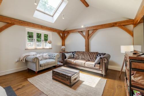 a living room with two couches and a skylight at Stable Cottage in Ringwood