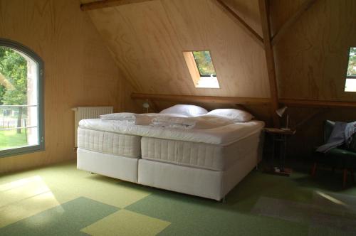 a bedroom with a white bed in a attic at Klein Dubbelland in Doorn