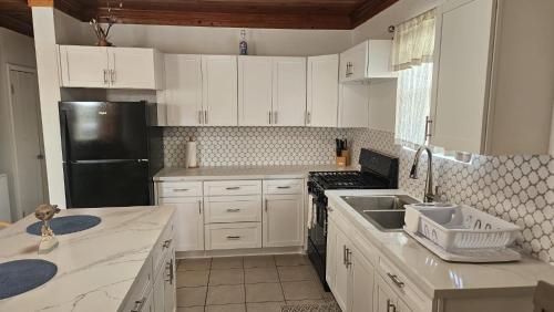 a kitchen with white cabinets and a black refrigerator at Tropical View Villas in Hartswell