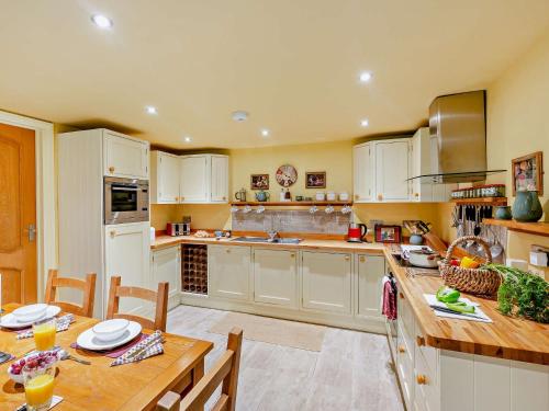a kitchen with white cabinets and a wooden table at 2 Bed in Lyonshall 93321 in Lyonshall