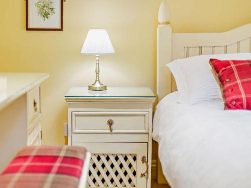 a bedroom with a bed and a lamp on a night stand at 2 Bed in Lyonshall 93321 in Lyonshall