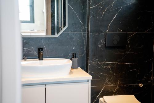 a bathroom with a sink and a black wall at Kalon Gaia NOSTOS in Karistos