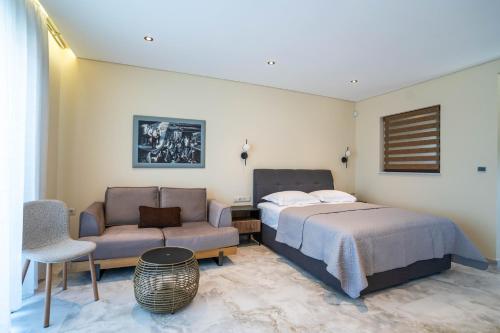 a bedroom with a bed and a couch and a chair at Kalon Gaia NOSTOS in Karistos
