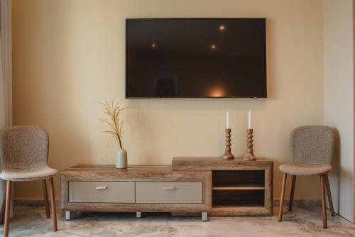 a living room with two chairs and a tv on the wall at Kalon Gaia NOSTOS in Karistos