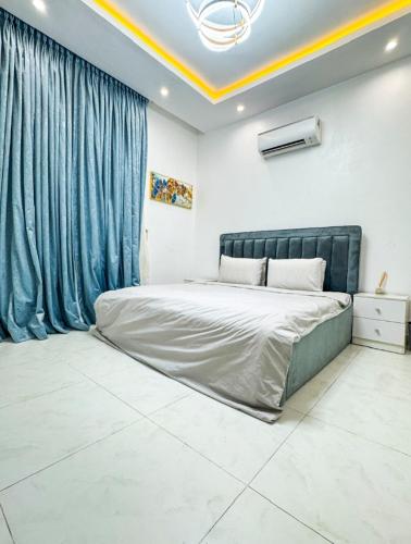 Un dormitorio con una cama grande y cortinas azules. en Exquisite Apartments, en Lagos