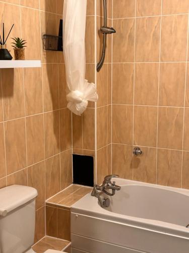 a bathroom with a tub and a toilet and a sink at Enjoy city living in this one-bedroom flat, complete with a balcony and secure parking in Birmingham city center in Birmingham