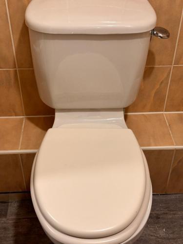 a white toilet in a bathroom with its lid down at Enjoy city living in this one-bedroom flat, complete with a balcony and secure parking in Birmingham city center in Birmingham