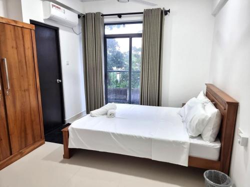ein Schlafzimmer mit einem Bett und einem großen Fenster in der Unterkunft Biyanka's lovely apartment in Sri Jayewardenepura Kotte