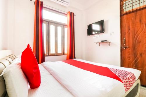 a bedroom with a bed with red pillows and a basketball hoop at Hotel O Arpit Hotel Jhusi Railway Station in Jhūsi