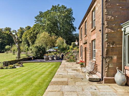 a brick house with a grass yard next to a building at 4 Bed in Wincle 95651 in Allgreave