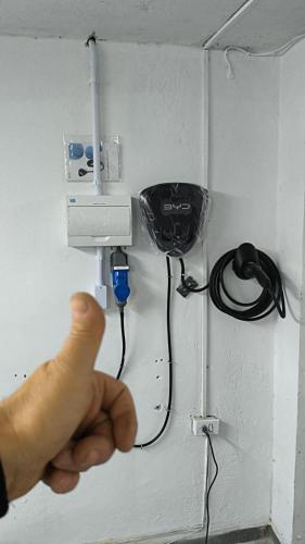 a person pointing at a electrical outlet on a wall at Apartamento conforto in Curitiba