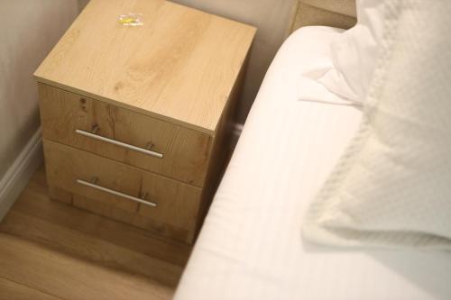 a bed with a wooden nightstand next to a white bed at Rooms Kruja City in Krujë