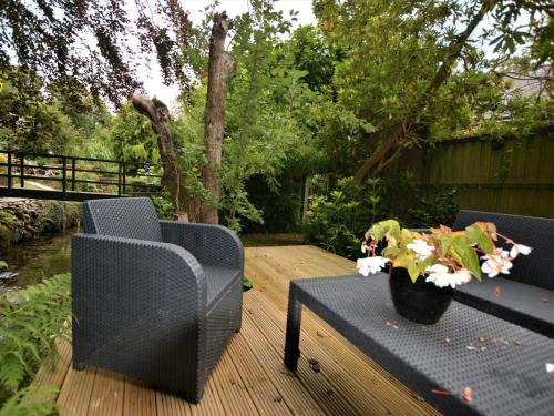 two chairs and a table with a vase of flowers on a deck at 3 Bed in Cenarth 79198 in Felindre