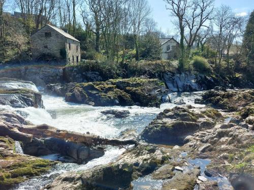 a river with rocks and a building in the background at 3 Bed in Cenarth 79198 in Felindre