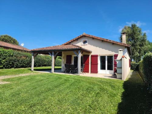 a house with a red door and a green yard at Spacious villa with garden and pool in Les Forges