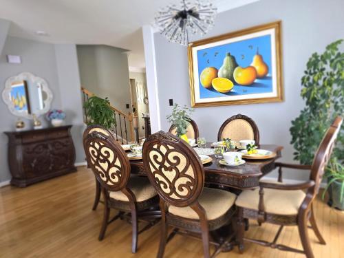 a dining room table with chairs and a painting of oranges at Loudoun Metro Station Home in Ashburn