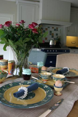 a table with plates and bowls and a vase with flowers at B&B Vallis Dyliae in Korbeek-Dijle