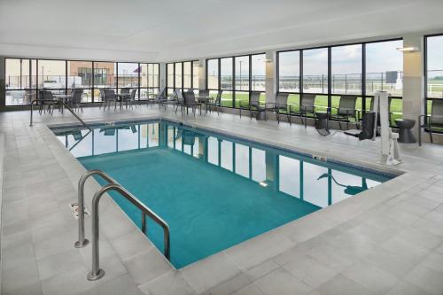 a swimming pool in a building with tables and chairs at TownePlace Suites by Marriott Columbus in Columbus