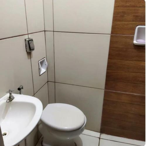a bathroom with a white toilet and a sink at Cantinho da Flor in Barretos