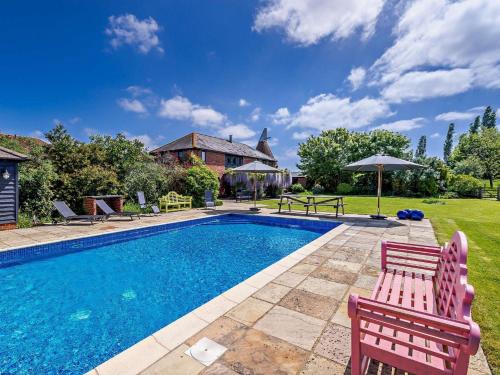 a swimming pool with two chairs and a house at 5 Bed in Smarden 76428 in Smarden