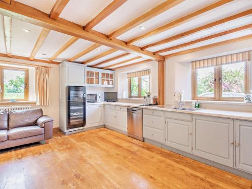 a kitchen with white cabinets and a couch in it at 5 Bed in Smarden 76428 in Smarden