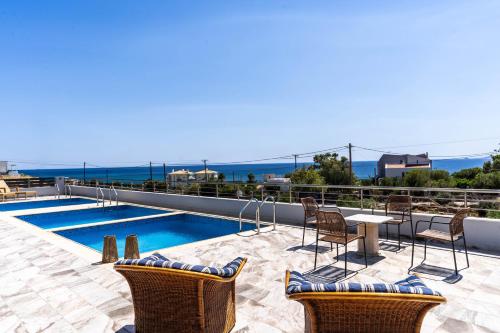 a patio with chairs and a table and a pool at Kalon Gaia NOSTOS in Karistos