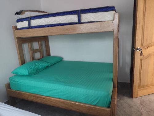 two bunk beds in a room with green sheets at Habitaciones con wifi a 5 minutos de la playa in Capurganá