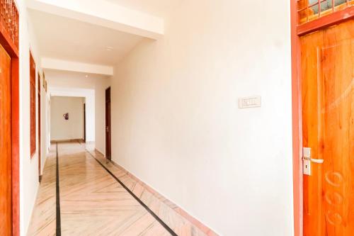 a hallway with white walls and a wooden door at Hotel O Arpit Hotel Jhusi Railway Station in Jhūsi