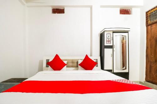 a bedroom with a white bed with red pillows at Hotel O Arpit Hotel Jhusi Railway Station in Jhūsi