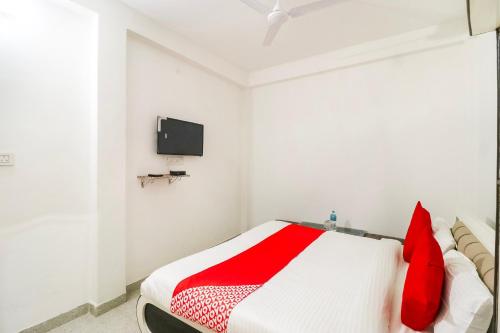 a bedroom with a bed with red pillows and a tv at Hotel O Arpit Hotel Jhusi Railway Station in Jhūsi