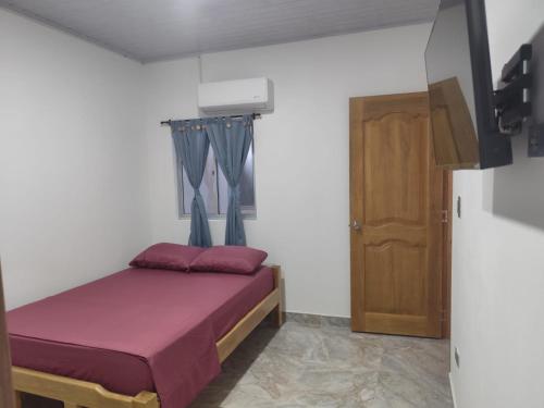 a bedroom with a bed with purple sheets and a door at Habitaciones con wifi a 5 minutos de la playa in Capurganá