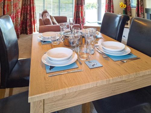 a wooden table with plates and glasses on it at Forrest Lodge in Plumbland