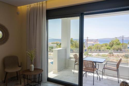 a living room with a table and chairs and a balcony at Kalon Gaia NOSTOS in Karistos